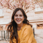 cheerful girl cashmere sweater laughs against backdrop blossoming sakura portrait woman yellow hoodie city spring